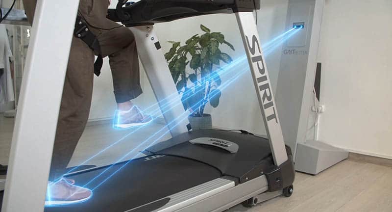 GaitBetter's virtual reality technology for gait training and to reduce fall risk is shown reading and calibrating the gait of an elderly patient as she walks on the VR treadmill in a physical therapy center