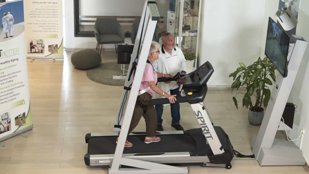 A physical therapist provides a therapy session with a patient on GaitBetter's virtual reality walking platform for gait rehabilitation and fall prevention