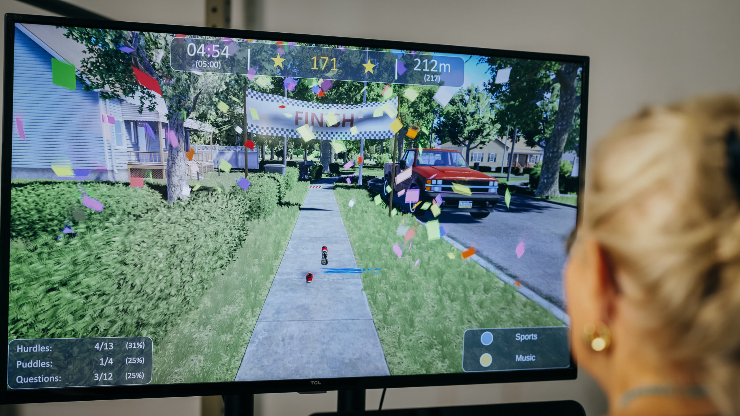 Older adult participating in interactive virtual reality gait training, shown from behind as they walk through a gamified exercise environment on a large screen.