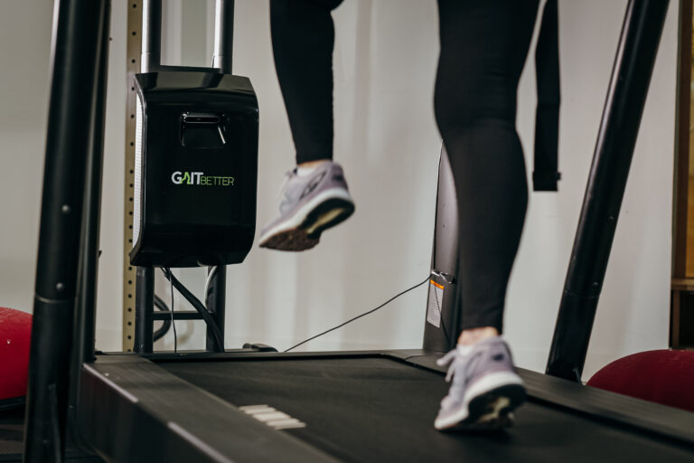 A close up of a person’s leg walking on a treadmill equipped with GaitBetter’s motor-congnitive training system